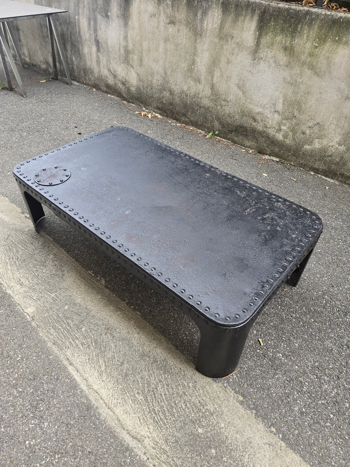 Table basse industrielle en métal riveté vers 1920 – patine noire – 145 × 80 cm